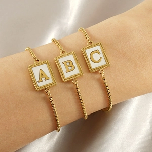 Detailed macro view of three layered gold shell initial bracelets with A B C letter charms