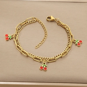 Close-up of double-layered gold chain bracelet featuring cherry pendants and lobster clasp