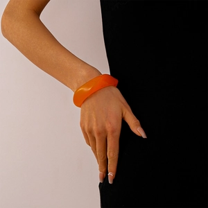 Close-up of a translucent orange acrylic bangle with irregular geometric resin design