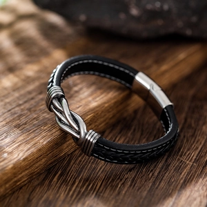 Men's double-row black leather bracelet with metal knot and magnetic clasp on wood
