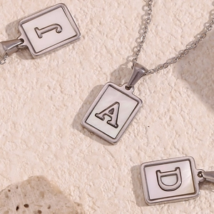 Detailed view of silver rectangular pendants with natural mother of pearl and letters