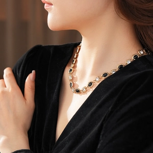 Gros plan d'un collier vintage doré avec pierre noire ovale et strass sur un mannequin