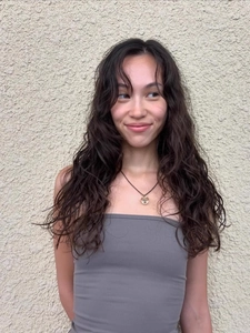 Detail of long wavy black brown synthetic hair extensions on model with natural waves
