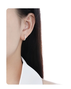 Close-up of minimalist silver hoop earrings with intricate floral carvings on model