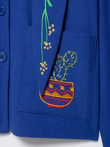 Macro shot of colorful floral cactus embroidery and woven fabric detail on a blue jacket