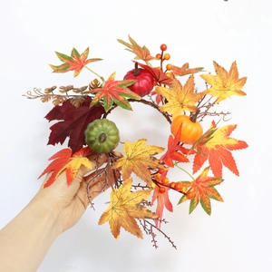 Detail of autumn candle ring with maple leaves, mini pumpkins, and red berries