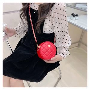 Detail of red quilted round crossbody bag for children with golden floral decor