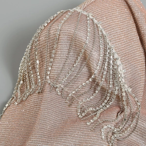 Detail of elegant shoulder tassels with rhinestones on a slim v-neck champagne jumpsuit