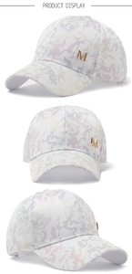 Detail of white mesh baseball cap with camouflage print and gold metal letter M buckle