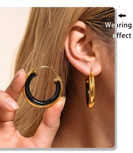 Close-up of gold-plated hoop earrings with black inlay showing the wearing effect