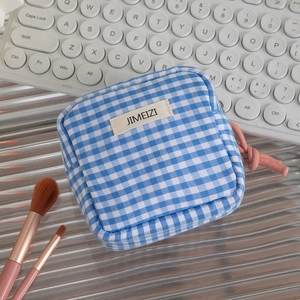 Detail of blue plaid storage bag with zipper and pink knot pull on office desk scene