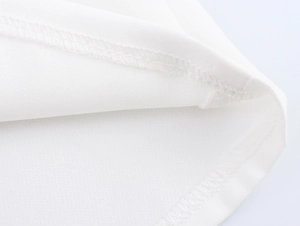 Gros plan d'un tissu blanc montrant une couture double de haute qualité sur l'ourlet