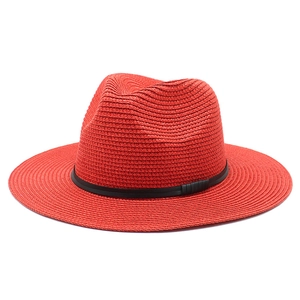 Detail of red straw Panama fedora hat with a thin black leather band on white background