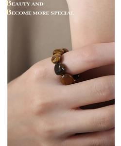 Detail of natural tiger eye stone elastic bead ring worn on finger with golden brown textures