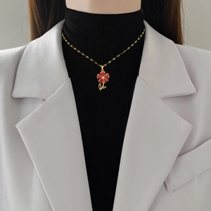 Elegant gold titanium steel necklace with a sparkling red flower pendant on a model