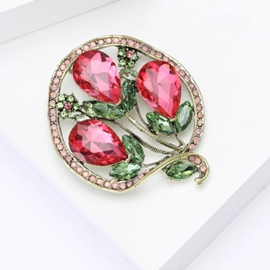 Detail of vintage bronze brooch with red teardrop crystals and green marquise gems