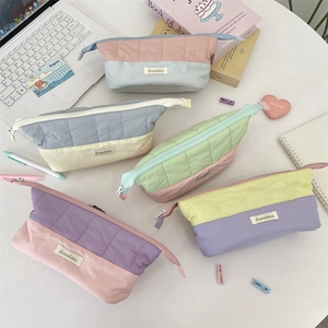 Detailed view of quilted two-tone pencil cases with Sozakka label on a white desk