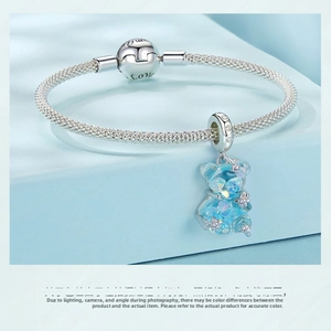 Macro view of a blue translucent bear charm with star rhinestones on a mesh silver bracelet