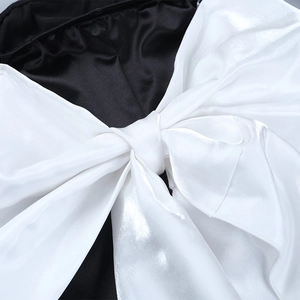 Gros plan d'un grand nœud en satin blanc sur une mini robe de soirée noire