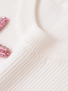 Detail of white ribbed knit collar with decorative pink beaded star ornaments