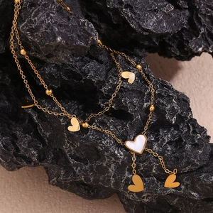 Detailed close-up of double-layer gold anklet with heart pendants and white shell inlay