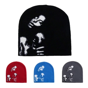 Detail view of knitted beanies in black, red, blue, and grey with human pattern prints