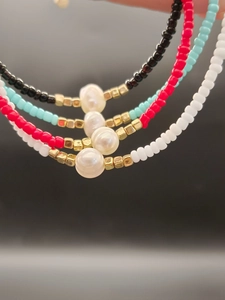 Macro shot of colorful beaded necklaces with freshwater pearls and golden cube accents