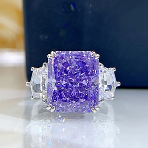Macro shot of Radiant Cut purple gemstone ring with side stones on a reflective base
