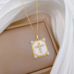 Titanium steel gold necklace with shell cross pendant and pearls on silk background