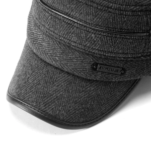 Macro detail of men's winter cap showing grey herringbone fabric and black leather trim