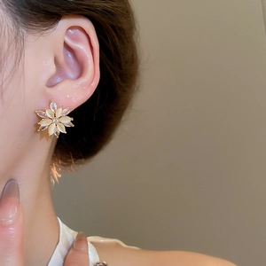 Detailed close-up of a floral earring with opal petals and shiny zircon on model