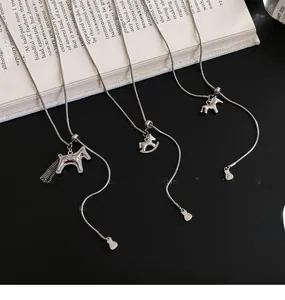 Detail view of silver necklaces with horse pendants and tassels on an elegant open book