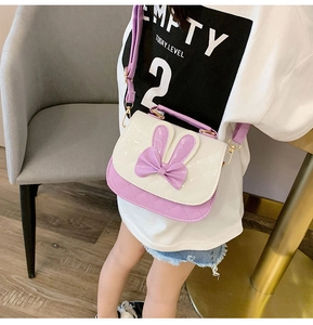 Detail of purple and white rabbit ear crossbody bag worn by child model indoors