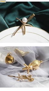 Macro shot of gold ocean-themed starfish shell hair clips with pearls on satin and mesh