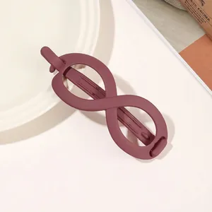 Detail of infinity-shaped matte purple hair claw clip displayed on a white ceramic plate