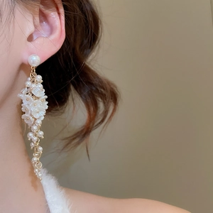 Detailed close-up of gold tassel earrings with elegant white pearl flower accents