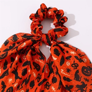 Détail macro du chouchou Halloween orange avec motifs de chauve-souris et citrouilles