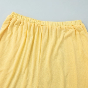 Detail of light yellow knit pants featuring a comfortable elastic waistband and ribbed texture