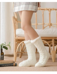 Close-up of white cable-knit winter floor socks with plush cuffs for home comfort