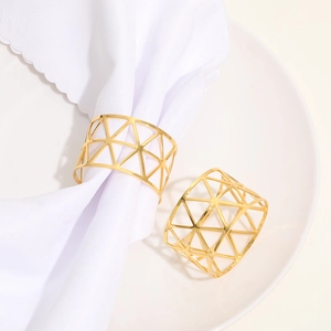 Golden metal napkin ring with geometric hollow design on a white ceramic plate