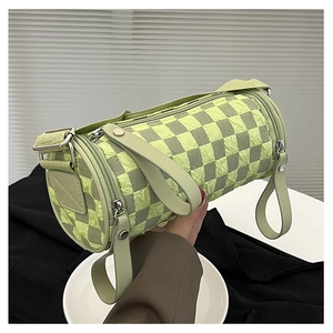 Detail of checkered barrel bag showing green textured fabric and adjustable strap