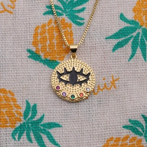 Macro detail of golden evil eye necklace with colorful zircons on a pineapple fabric