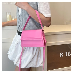 Chic pink crossbody bag with wide strap shown in a stylish outdoor cafe street setting