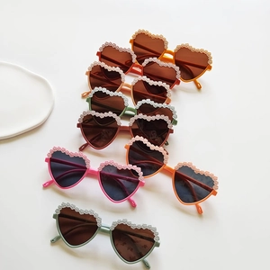 Flat lay of colorful heart-shaped kids sunglasses with decorative lace frame edges