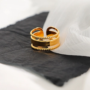 Detail of layered gold ring showing smooth bands and twisted rope texture on dark base
