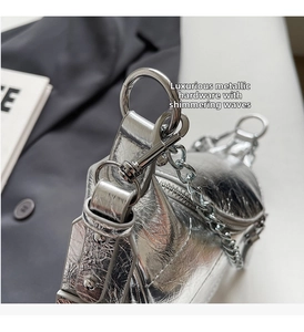 Detailed macro view of metallic silver saddle bag with polished chrome hardware and chain