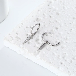 Macro detail of S925 silver hoop earrings with sparkling zircon-studded cone pendants
