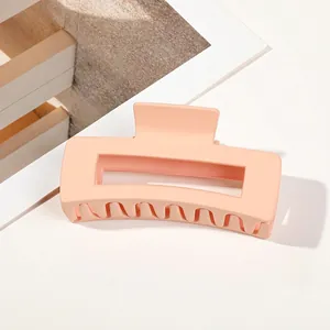 Detail of a peach matte rectangular hair claw clip with cutout design on white background