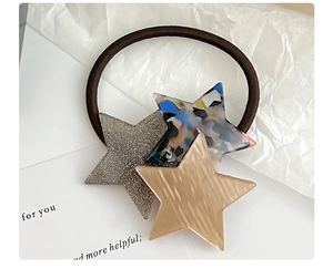 Close-up of star-shaped hair tie with glitter and marble textures on brown elastic