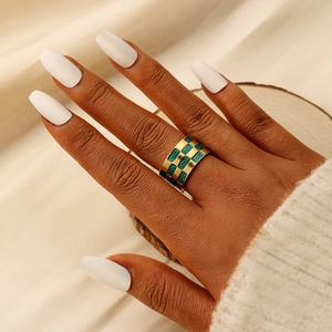 Detailed view of wide gold brushed steel ring with green checkered enamel on hand